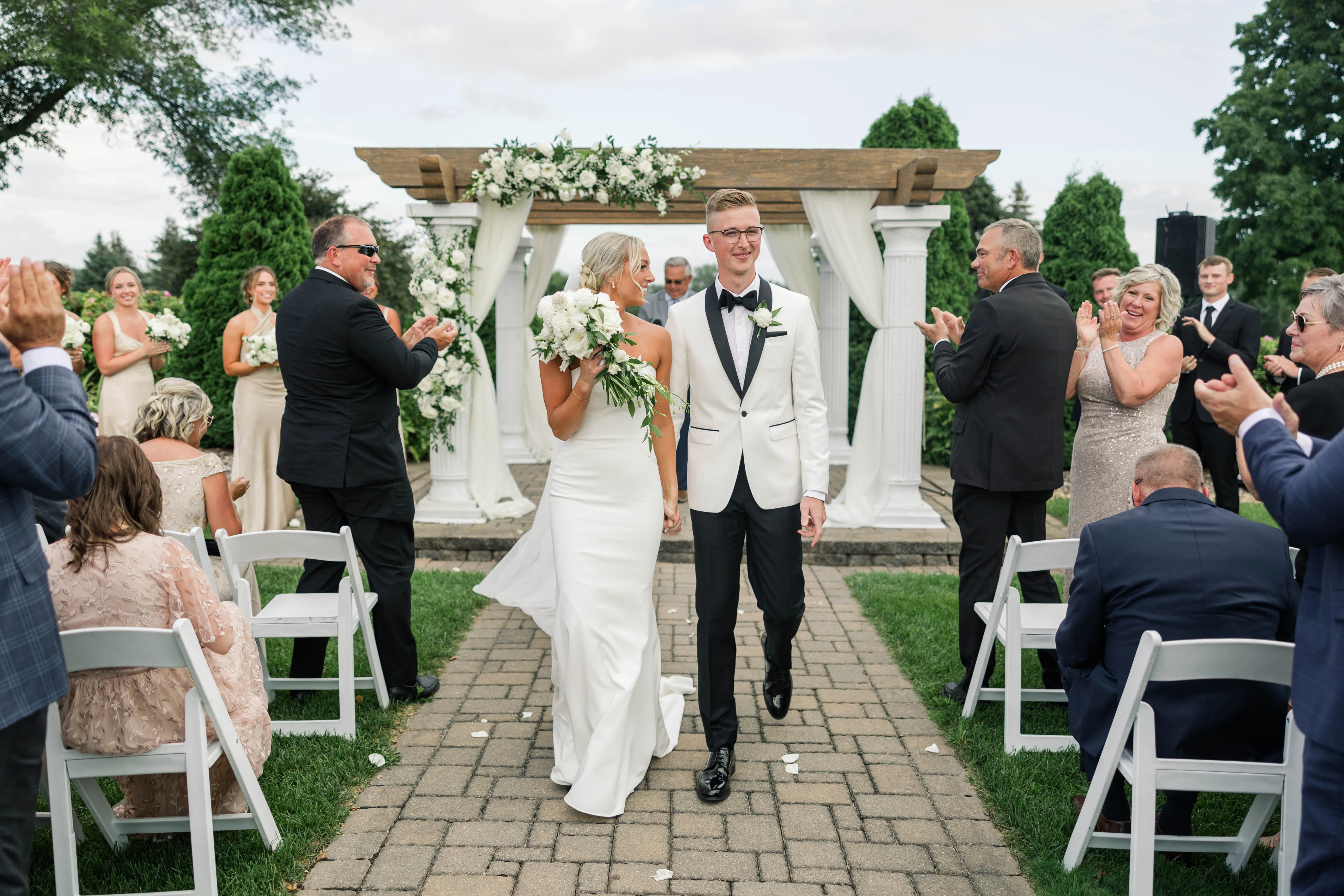 Bride wearing Francine sheath wedding dress by Rebecca Ingram walking back down the aisle after her ceremony with her husband.